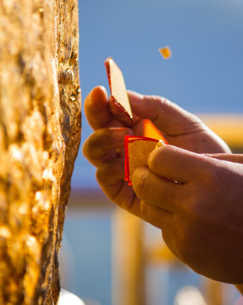 A devotee pasting gold leaves to the Golden Rock at the Kyaiktiyo Pagoda (Photo: iStockphoto)