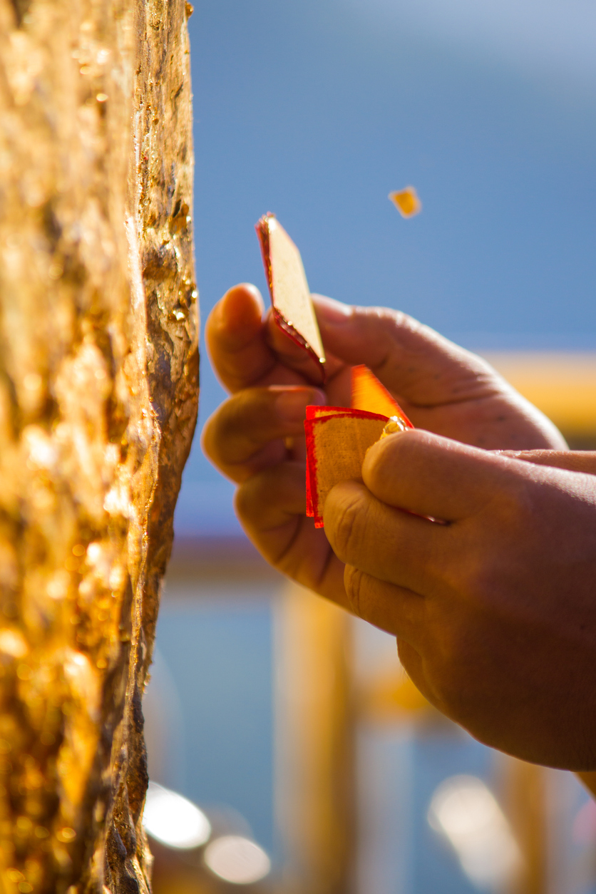 ผู้เลื่อมใสศรัทธาในองค์เจดีย์กำลังปิดทองที่ฐานเจดีย์พระธาตุอินทร์แขวน (รูปภาพ: iStockphoto)