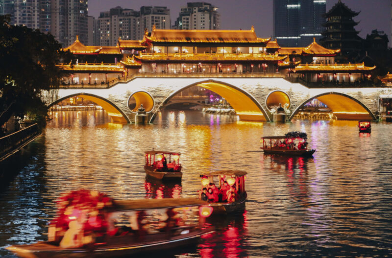 Embark on a serene boat ride along the Jinjiang River and witness the captivating beauty of Anshun Bridge illuminated under the night sky. (Photo Credit: iStockphoto)