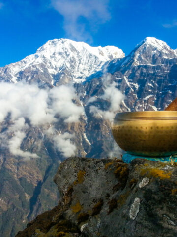 Brass singing bowls set against the backdrop of the Himalayan Mountain range. (Photo Credit: iStockphoto)