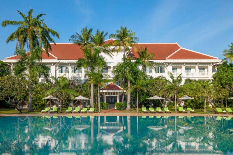 The view of the grand mansion with a swimming pool as a foreground.