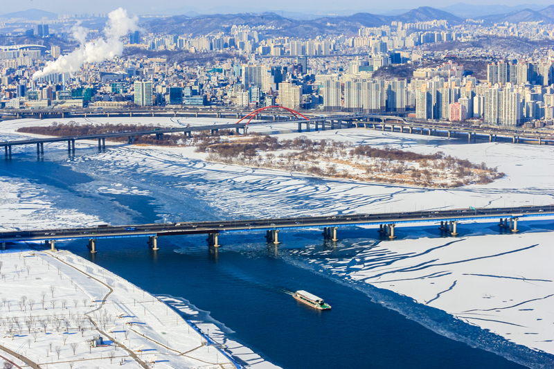 A winter view of Seoul and the Han River, covered in snow and ice.