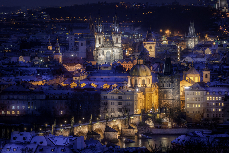 Winter light bathes Charles Bridge and Old Town Square, turning T&yacute;n Church into a golden silhouette.