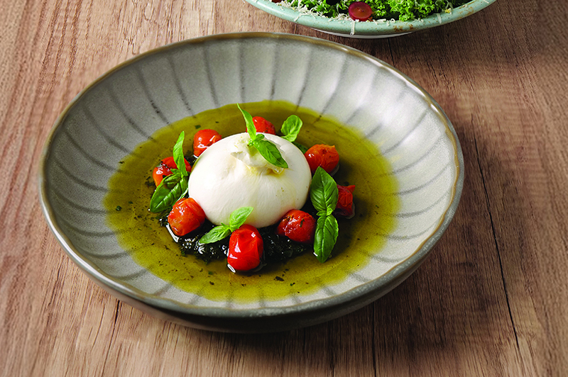 Khao Yai burrata with organic pesto and grilled cherry tomatoes is a perfect pairing with a glass of wine.