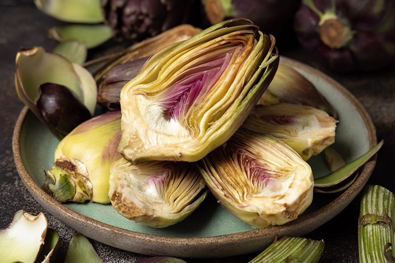 Plate full of cut purple raw romanesco artichokes.
