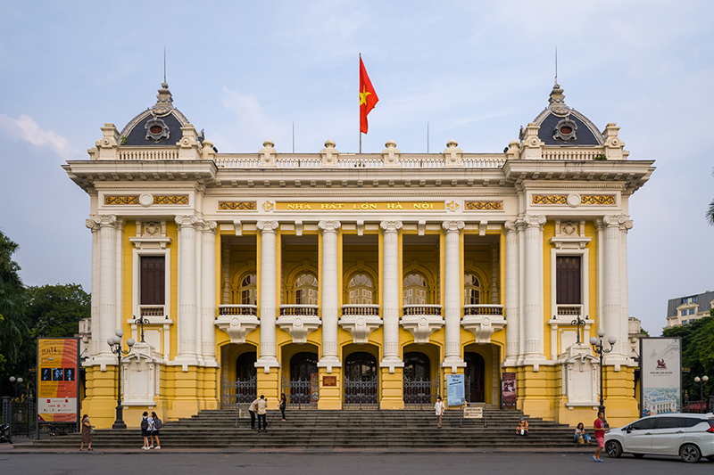 The facade of the Hanoi Opera House features yellow and white colonial architecture.
