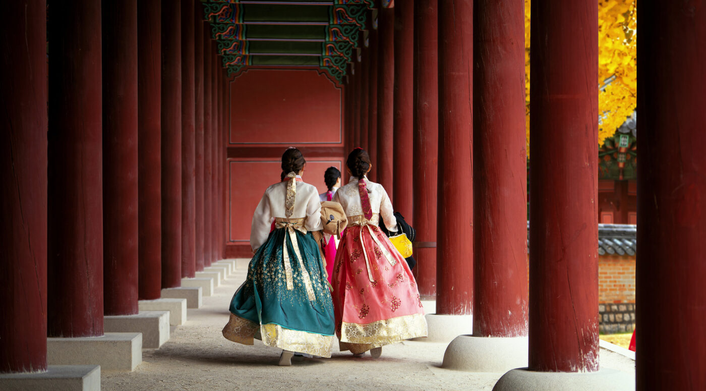 Girls wearing traditional hanbok stroll through the historic palace.
