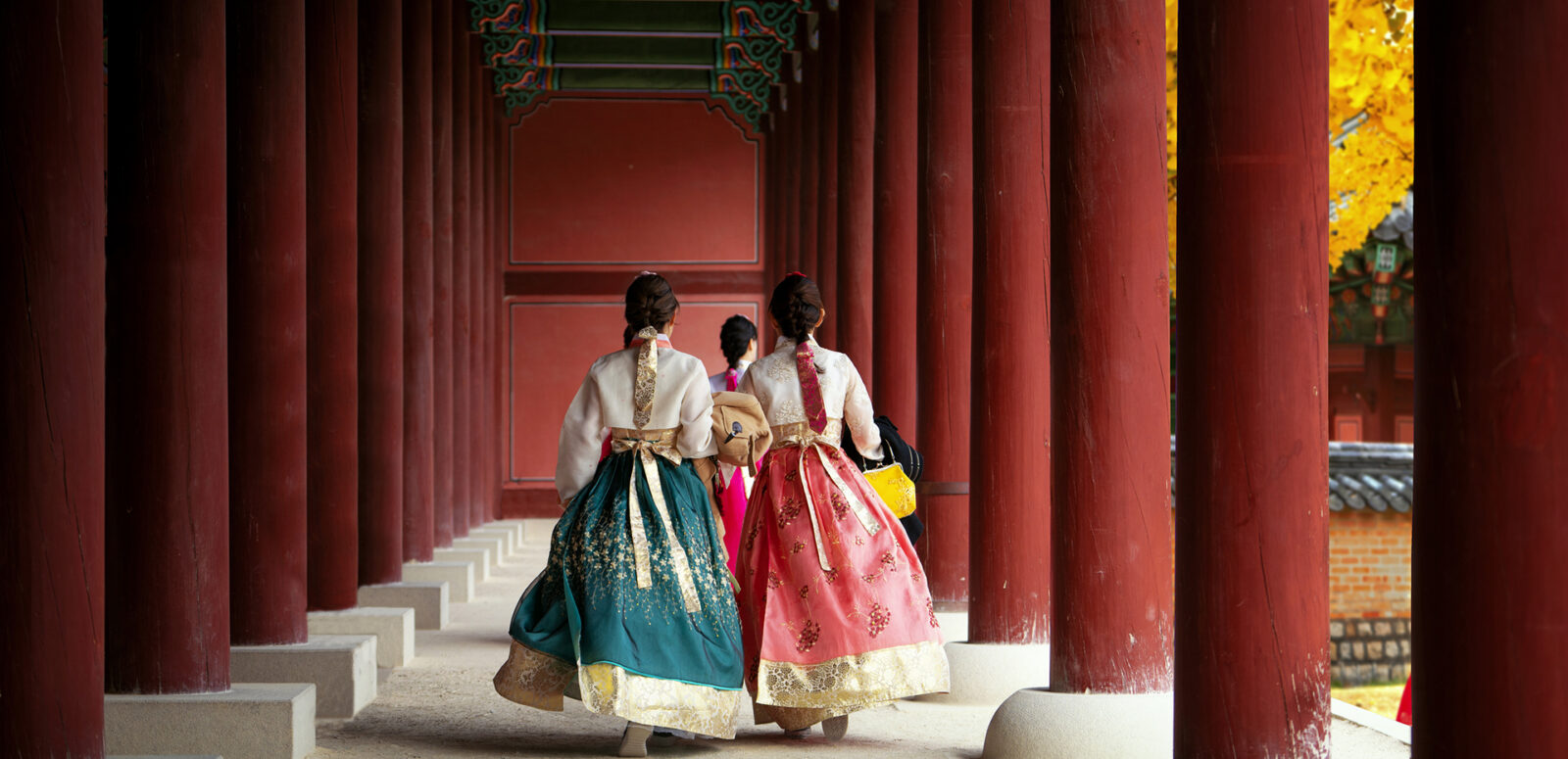 Girls wearing traditional hanbok stroll through the historic palace.
