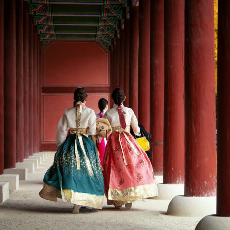 Girls wearing traditional hanbok stroll through the historic palace.