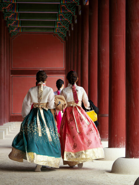 Girls wearing traditional hanbok stroll through the historic palace.
