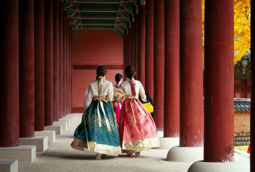 Girls wearing traditional hanbok stroll through the historic palace.