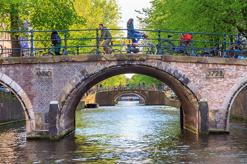 Amsterdam, The Netherlands - May 2, People ride their bikes over the famous canal bridges of Amsterdam.