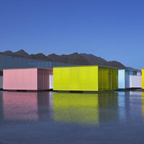 Eight movable 10-meter galleries float across the basin, each wrapped in a distinct shade of luminous colored glass.