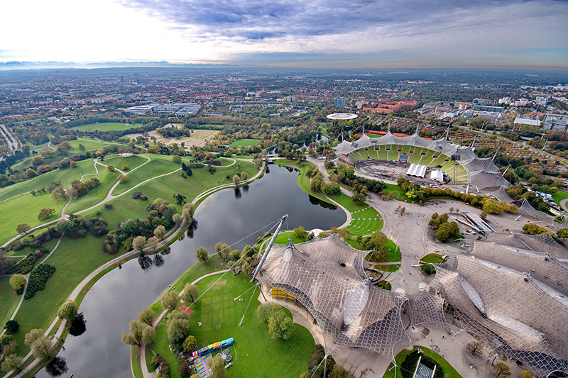 A wide-angle aerial photograph of the Munich Olympiapark landscape from the top of the TV Tower.